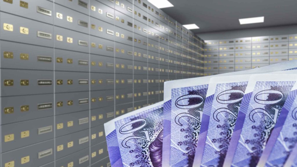 cash held in front of a safe deposit vault